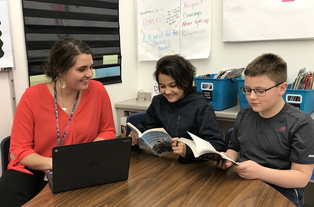 Teacher working with student, with class working independently.